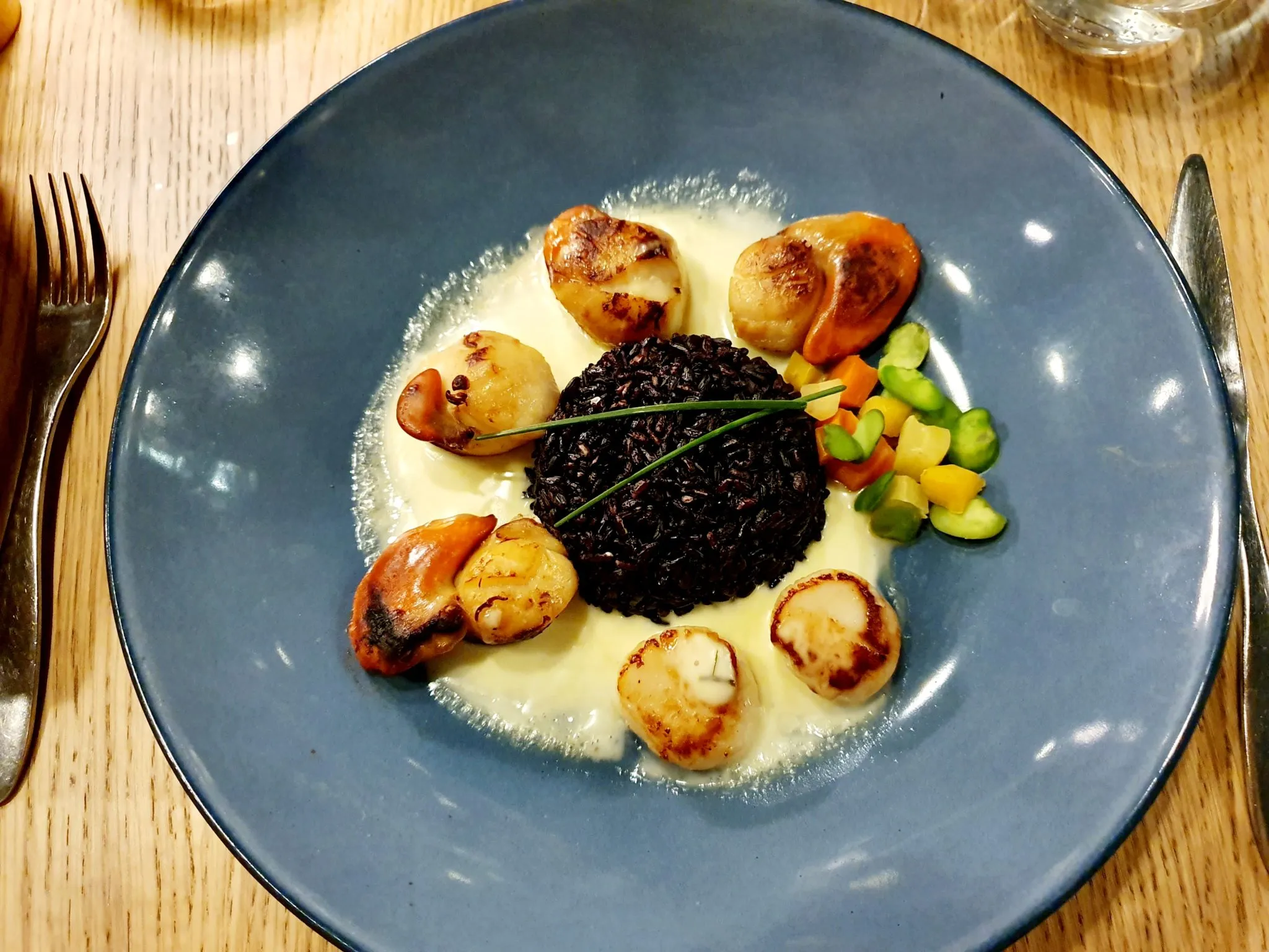 The perfectly cooked scallops main course served with black rice and a butter sauce, a highlight of the seafood selection on the et restaurant menu