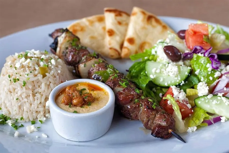 A display of various char-broiled souvlaki skewers and side dishes