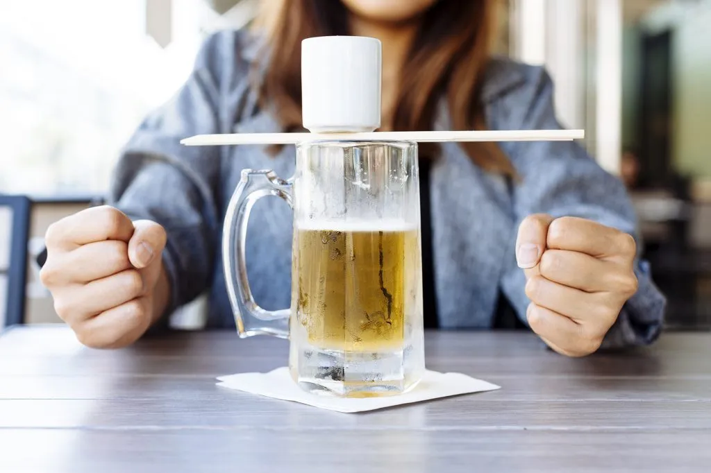 A Japanese 'sake bomb' is being prepared, showing a glass of beer with a small cup of sake balanced on top.