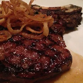 A perfectly grilled bone-in rib eye steak, showcasing excellent marbling and char on a serving platter