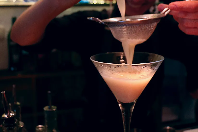 A bartender's close-up view crafting a vibrant cocktail with fresh ingredients, showcasing Ombú Restaurant's innovative new menu in Palma.