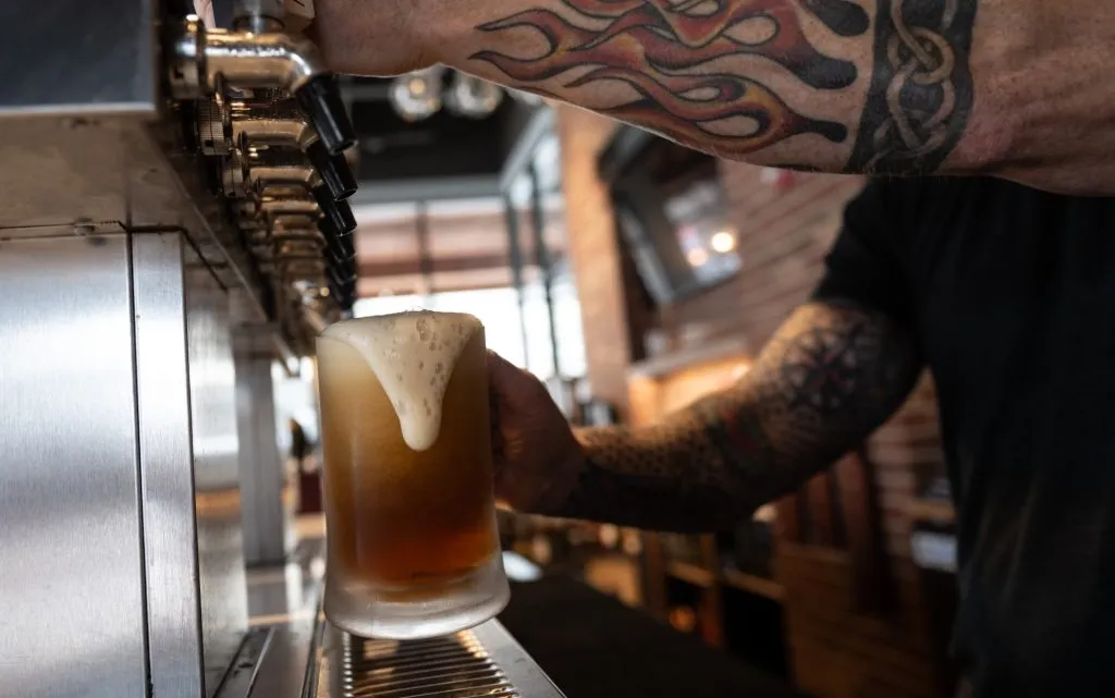 A bartender pouring a drink at Capitol Public House, highlighting the extensive beverage options available alongside the eagle family restaurant menu