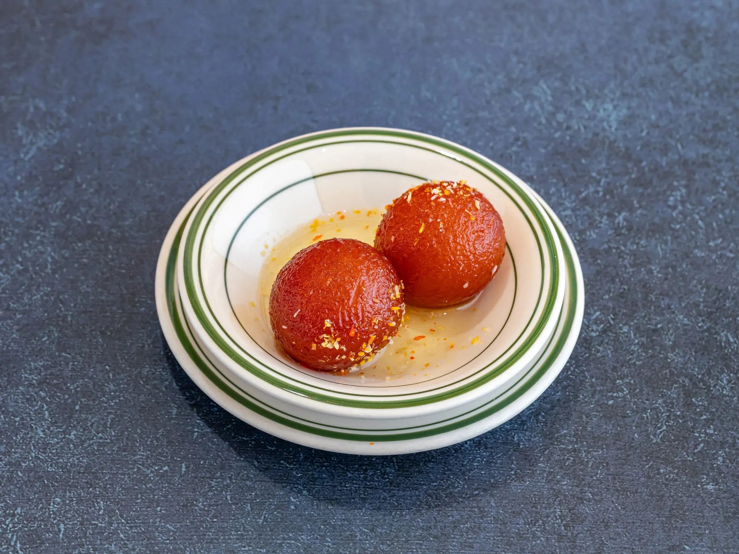 Gulab Jamun, a beloved sweet from our bollywood indian restaurant menu, soft cheese balls soaked in sweet syrup.