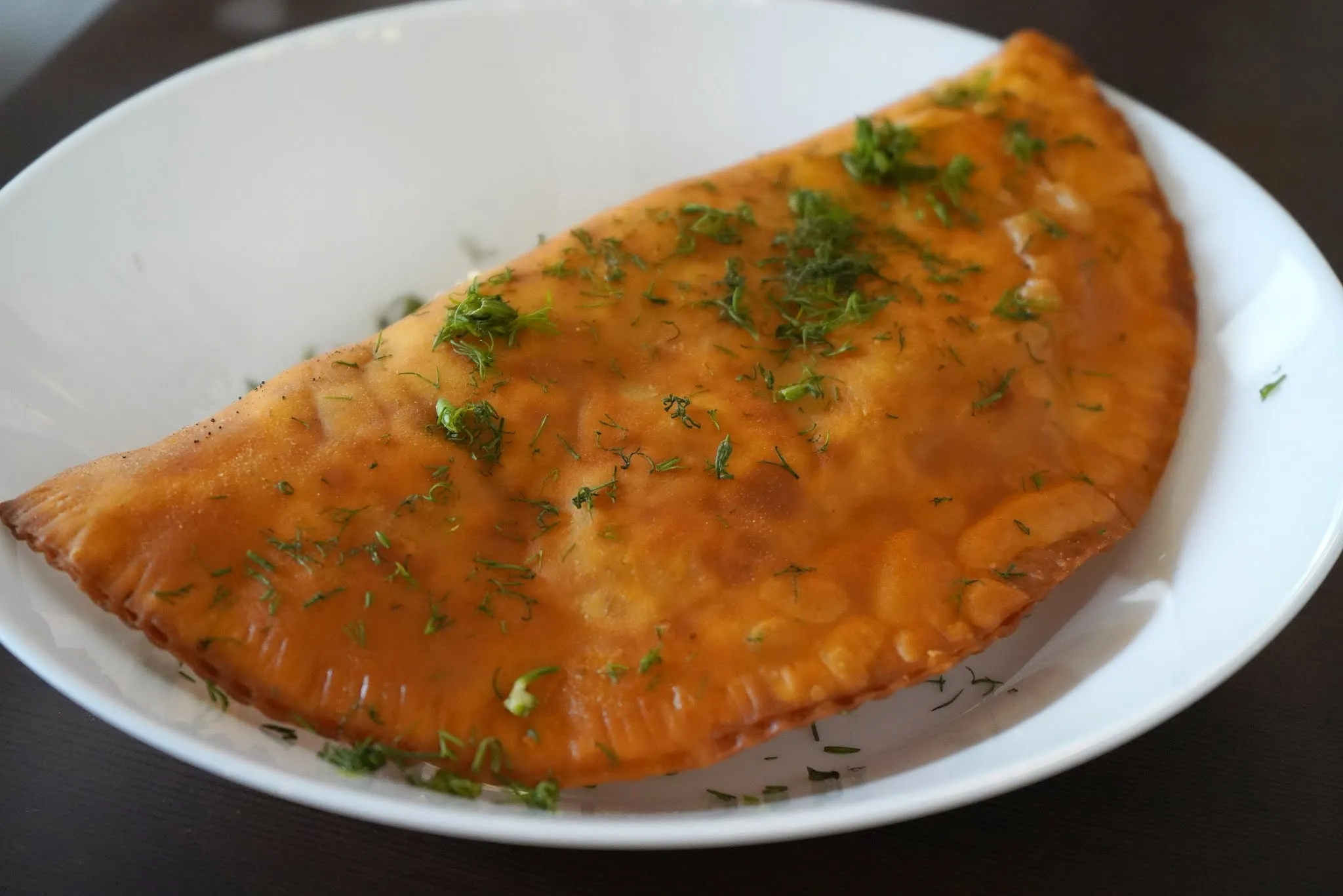 Golden-brown Chebureki, a deep-fried savory pastry from a Russian menu restaurant, filled with minced meat