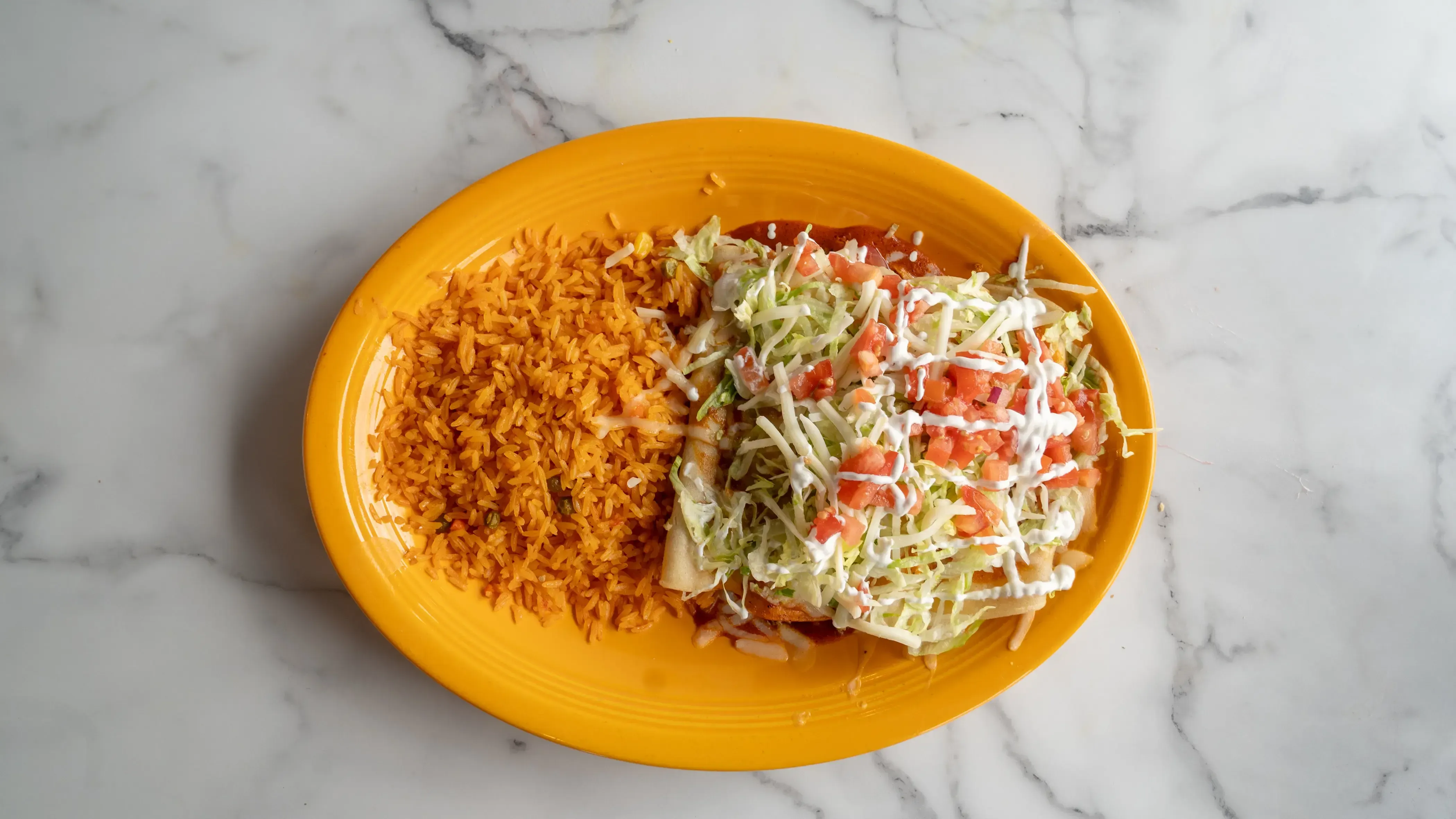 Enchiladas supremas - Four enchiladas featuring chicken, cheese, bean, and beef, topped with red or green sauce, melted cheese, lettuce, tomatoes, and sour cream. Served with Mexican rice