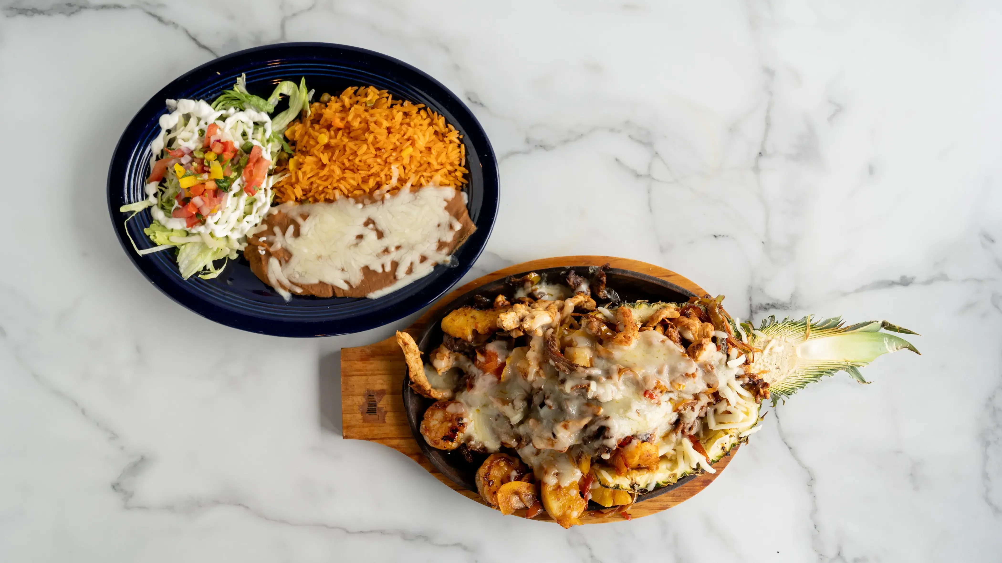 Fajita Hawaiana - Tropical sizzling combination of grilled steak, chicken, shrimp, and pineapple with bell peppers, onions, and tomatoes. Served with rice, beans, lettuce, sour cream, cheese, pico de gallo, and three tortillas