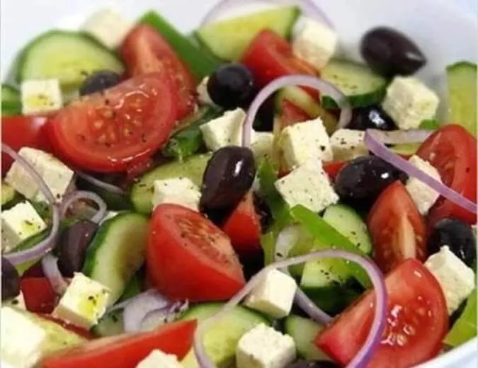 A classic Small Greek Salad with ripe tomatoes, cucumbers, Kalamata olives, and a block of Feta