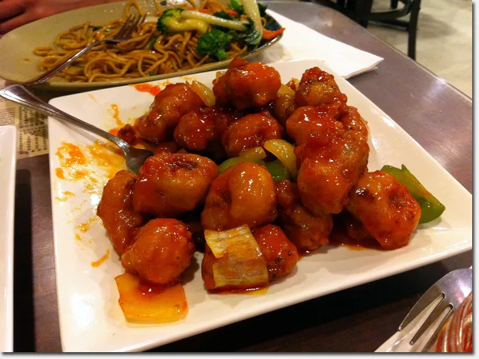 A vibrant sweet and sour pork dish, a classic offering from the extensive green island chinese restaurant menu, presented with crispy pork pieces in a tangy sauce, alongside rice, a popular Chinese-Vietnamese culinary choice.