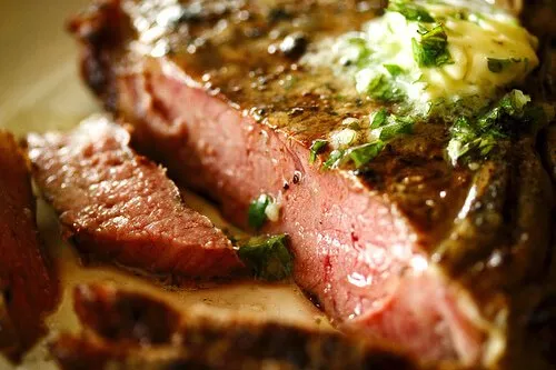 A perfectly grilled steak topped with a melting pat of compound herb butter