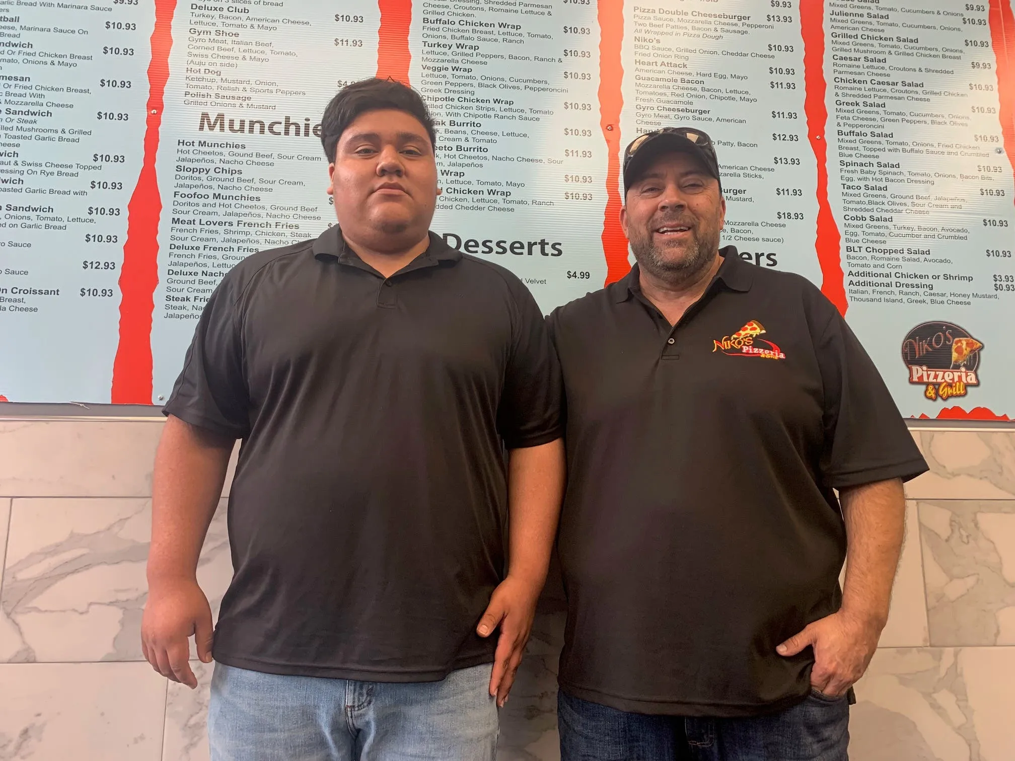 Niko's Pizzeria manager Jose Verdin and new owner Gabriel Jaramillo discussing the extensive niko's restaurant menu offerings.