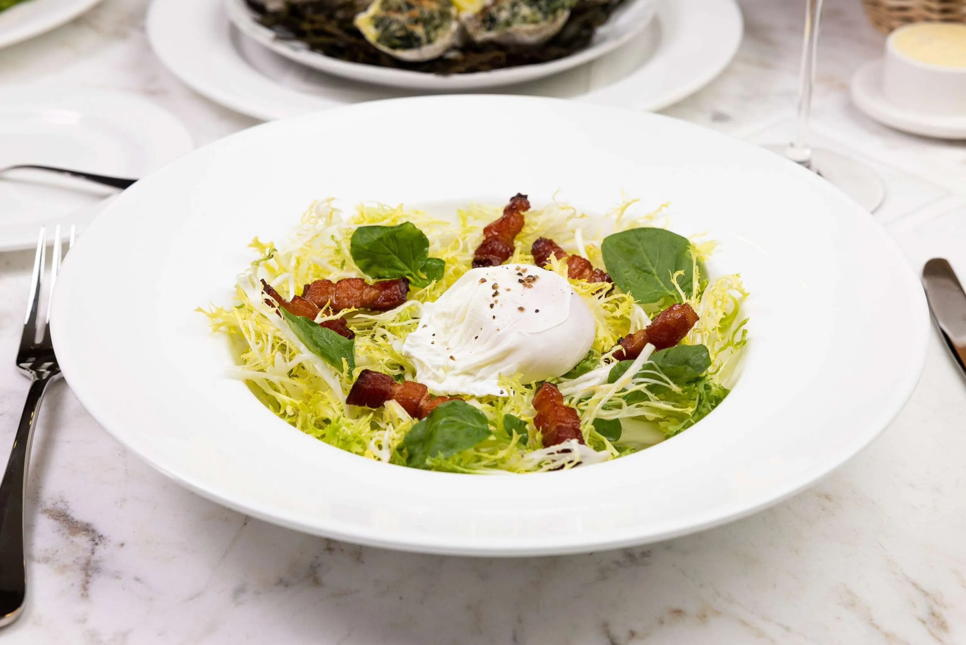 A vibrant Frisée Salad, offering a crisp, fresh option from the diverse Stewart's restaurant menu.