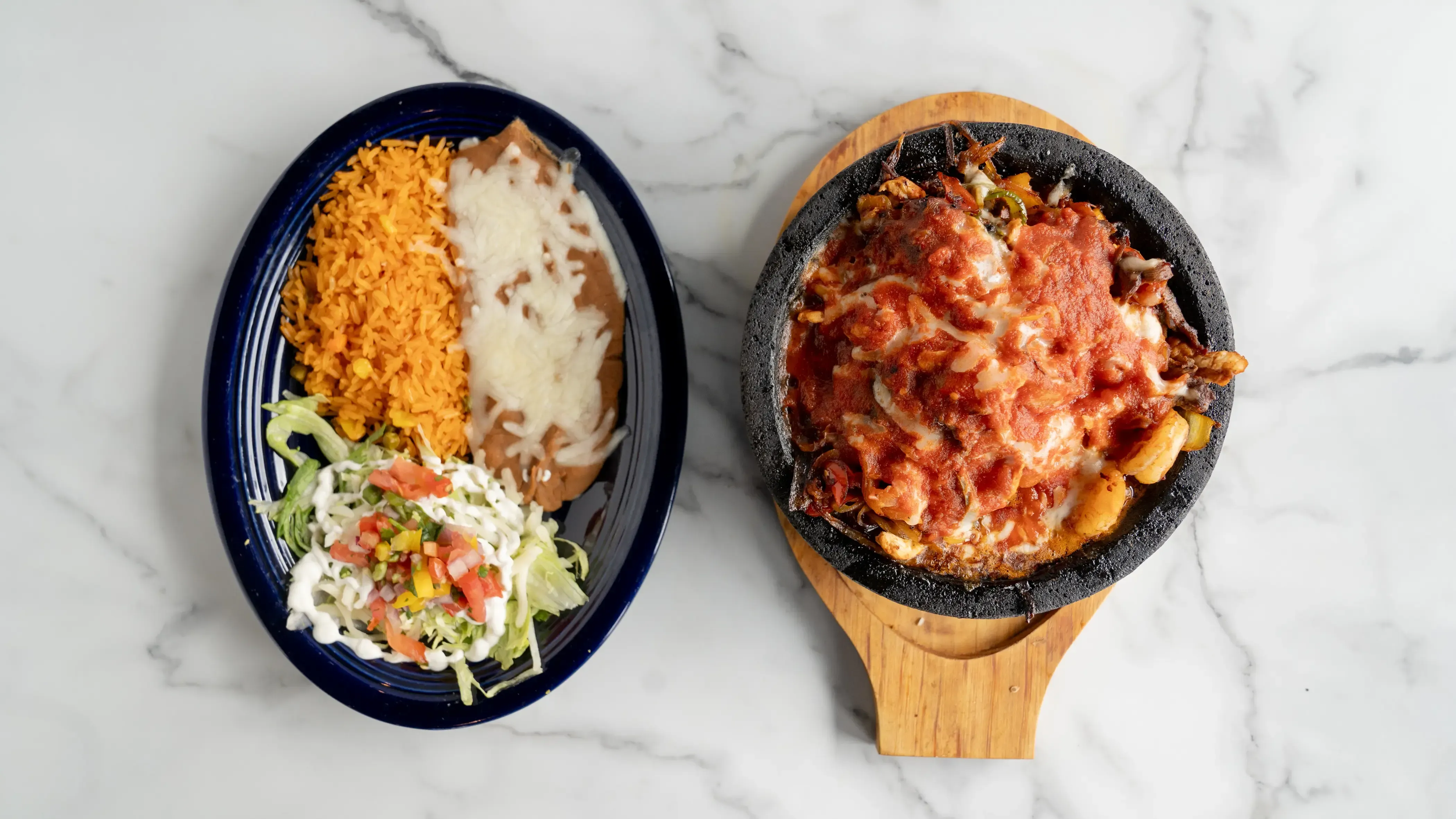 Molcajete - Grilled steak, chicken, and shrimp with bell peppers, onions, tomatoes, and pineapple, topped with Monterrey Jack cheese and special red sauce. Served sizzling in an authentic Mexican molcajete with rice, beans, sour cream, lettuce, pico de gallo, and three tortillas