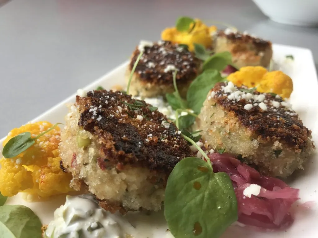 Exquisitely plated Blue Fin Crab Cakes, served with charred lemon, pickled vegetables, and jalapeno tartar sauce from the moxie's restaurant menu