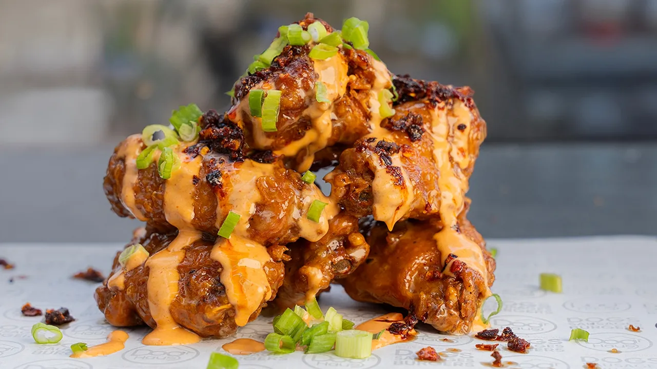 Dog Haus Mighty Moa Wings, tossed in a teriyaki aïoli and topped with spicy mayonnaise, chili crisp, and scallions, proving the commercial viability of an intensely umami-rich LTO