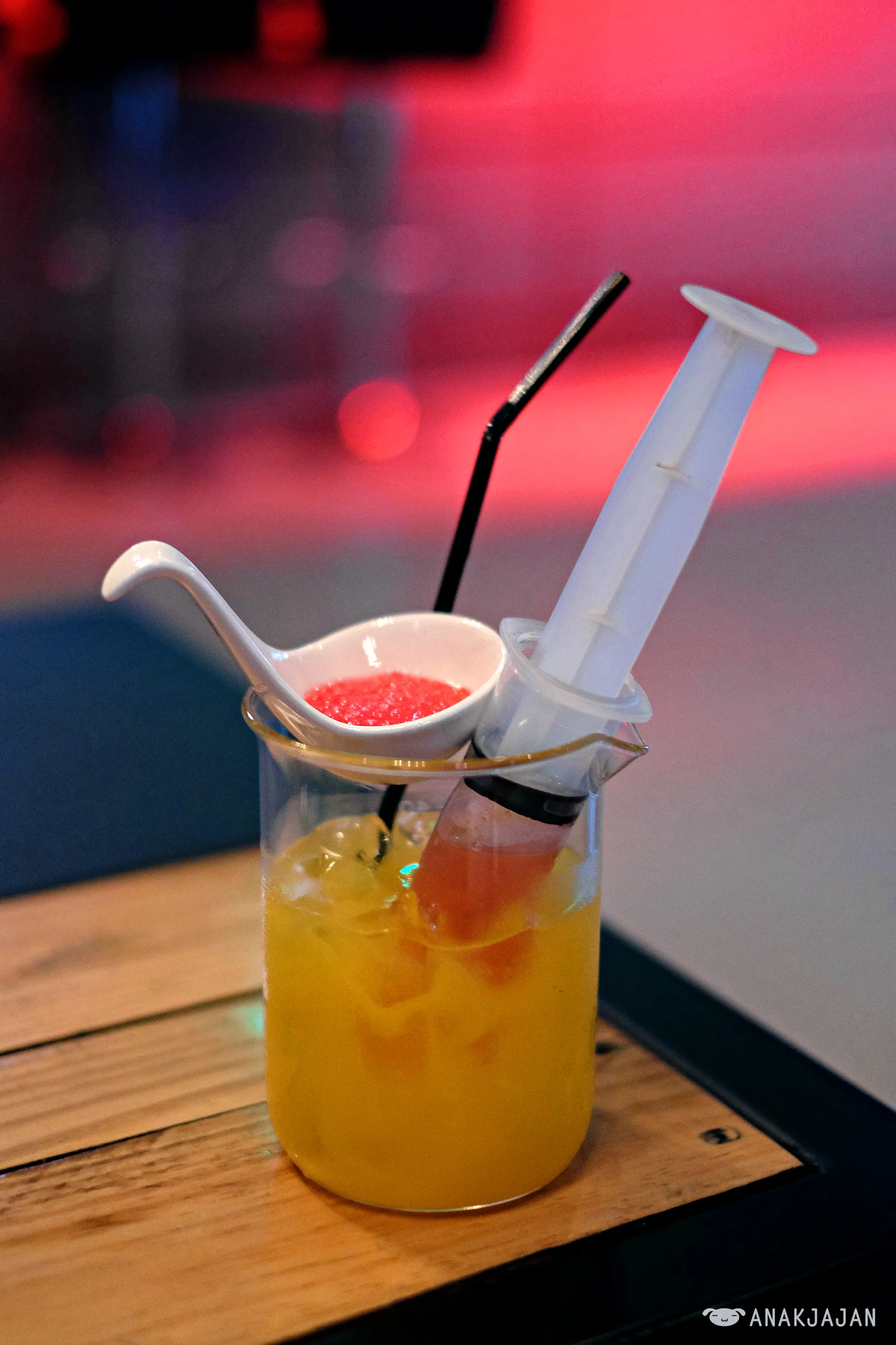 Local Anesthetic mocktail served in a glass with a syringe and caviar mocktail spheres